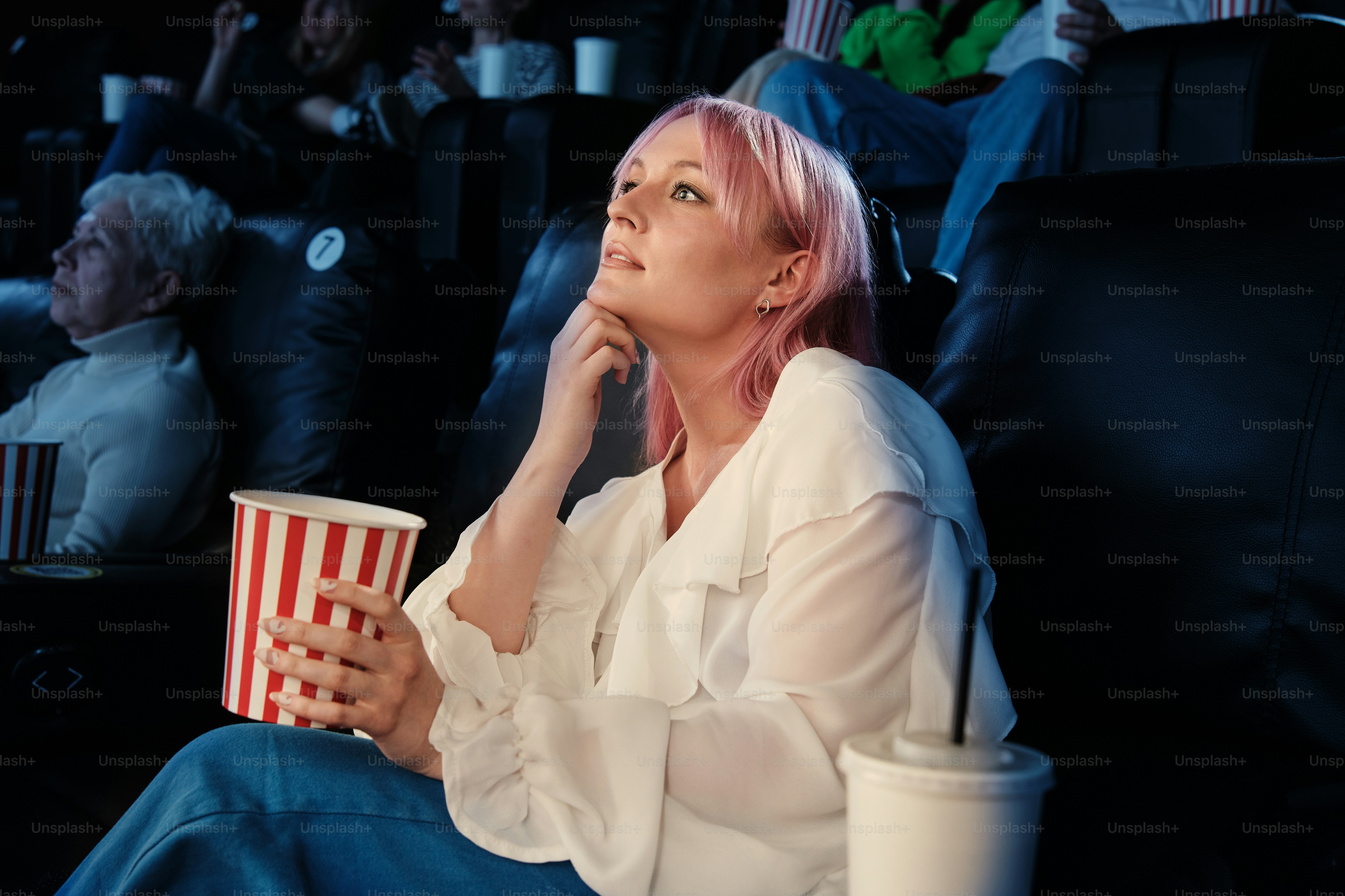 portrait of a woman sitting in a movie theatre watching a movie